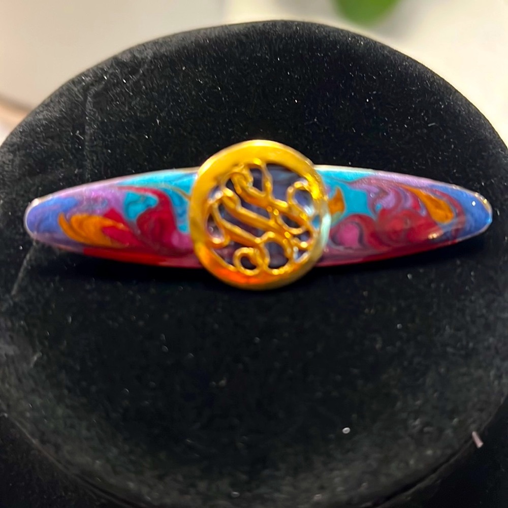 Multicolored brooch with gold round disc.